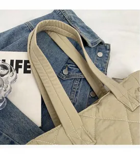 Close-up of comfortable padded handles on a beige quilted nylon tote bag