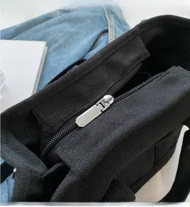 Detail of a smooth silver metal zipper on a premium black canvas tote bag