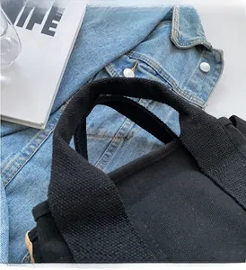 Detailed close-up of durable reinforced canvas handles on a large black tote bag
