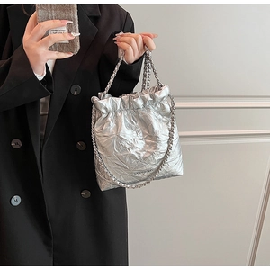 Detail of silver metallic drawstring bucket bag with quilted texture and chain strap