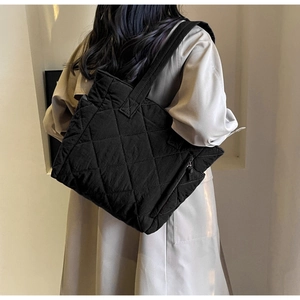 Detail view of black quilted nylon tote bag with rhombus pattern and side zipper