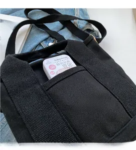 Detail view of the black canvas bag front pocket showing storage space and fabric texture
