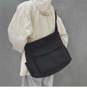Vista posteriore della modella con una grande borsa a tracolla in tela nera con tasche