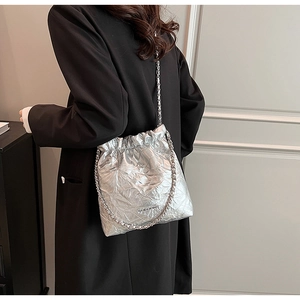 Silver metallic bucket bag with quilted design and chain strap worn over the shoulder