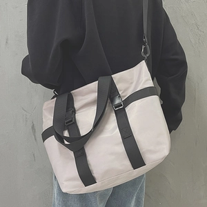 Minimalist beige tote bag with black nylon straps shown from a stylish back-view perspective