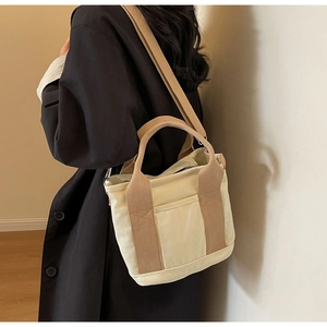 Detailed view of cream canvas tote bag with brown straps worn as a crossbody bag