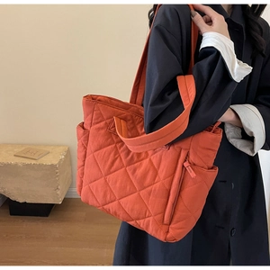 Detail of orange quilted nylon tote bag featuring side pockets and spacious commute design