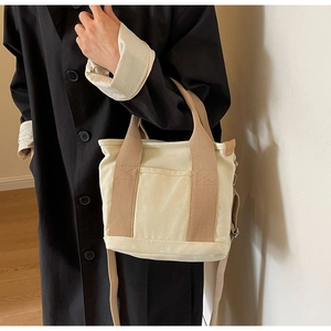 Detail of a large capacity canvas tote bag featuring double handles and a front pocket