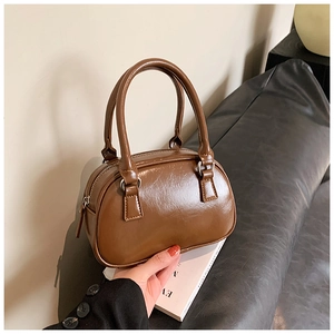 Detailed macro view of the glossy brown vintage small Boston bag with silver buckles