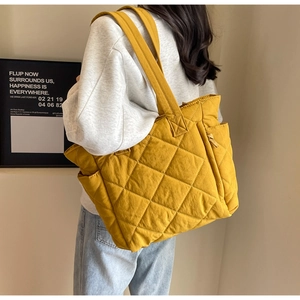 Quilted yellow nylon tote bag side pocket and thick shoulder straps shown on model