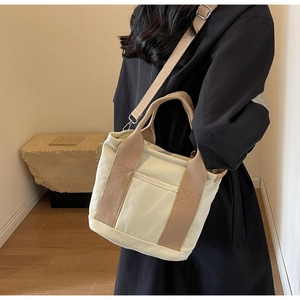 Detail of canvas tote bag with adjustable strap and contrast pocket on neutral background