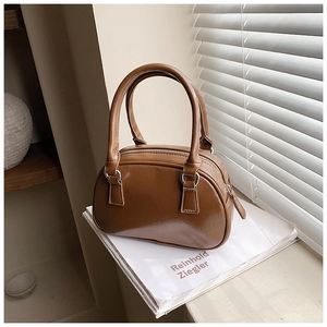 Macro detail of brown bowling-style handbag with glossy leather texture and double handles