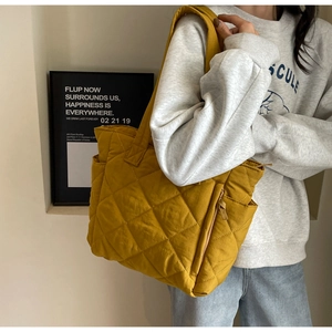 Detail of a bright lemon yellow puffer tote bag with quilted diamond pattern