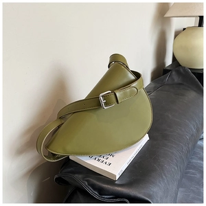 Borsa a mezzaluna verde avocado con tracolla regolabile su sfondo di libro artistico