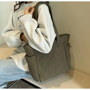 Detail view of large quilted nylon tote bag with rhombus pattern and wide shoulder strap