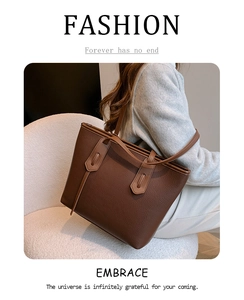 Detail of dark brown tote bag with pebble leather texture and long shoulder strap