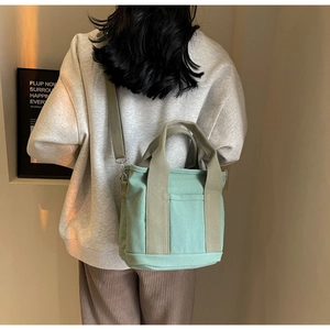 Detail of light green canvas tote bag showing adjustable strap and shoulder wear style