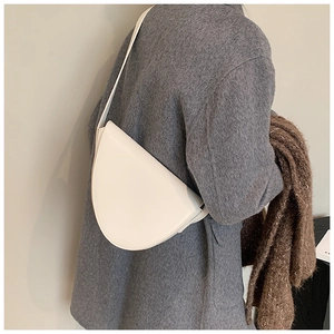 Borsa a tracolla bianca minimalista indossata dal modello con cappotto grigio e sciarpa