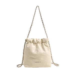 Beige quilted drawstring bucket bag with elegant chain strap and polished metal logo