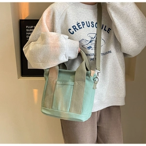 Detail of mint green canvas bag with front pocket and durable woven handles