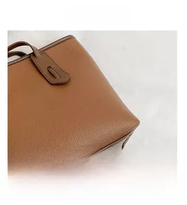 Detail of brown lychee grain leather tote showing fine stitching and smooth edge oil