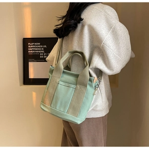 Side view of mint green canvas tote bag being worn as a crossbody shoulder bag