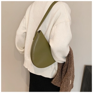 Borsa a spalla minimalista verde oliva a forma di goccia indossata da una modella elegante
