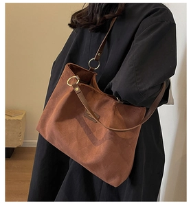 Close-up of brown suede tote bag featuring embossed rhombus pattern and leather straps