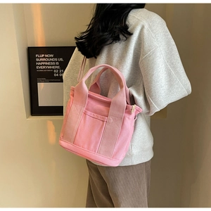 Pink canvas crossbody bag featuring a spacious front pocket and wide woven handles