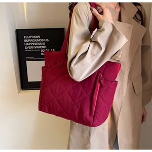 Detail view of burgundy quilted nylon tote bag with side zipper and elegant stitching