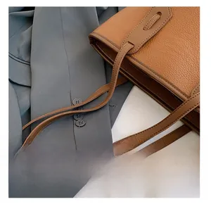Close-up of caramel brown pebble leather tote bag handle and stitching detail