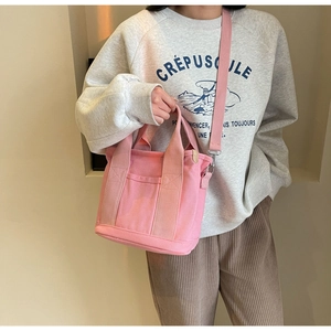 Detail of pink canvas mini tote with adjustable shoulder strap on female model