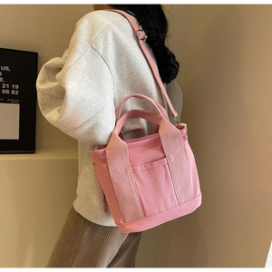 Pink canvas tote bag shown as shoulder bag style with adjustable straps and front pocket