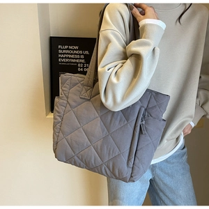 Detailed side view of a gray quilted nylon tote bag with shoulder straps and side pocket