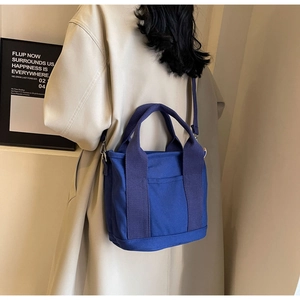 Detail view of a blue canvas tote bag featuring a front pocket and detachable shoulder strap