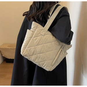 Detail of quilted diamond pattern and side pocket on a cream nylon tote bag