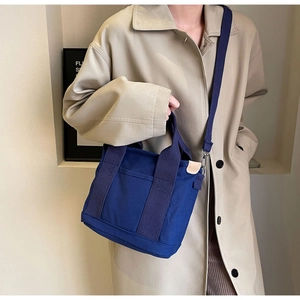 Detail of navy blue canvas tote bag with front pocket and adjustable shoulder strap