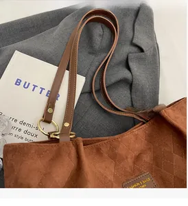 Detail of vintage brown suede tote bag with diamond lattice pattern and leather tag