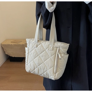 Lifestyle shot of beige quilted nylon tote bag worn by a model for daily commuting fashion