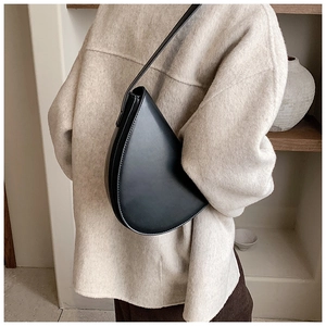 Borsa a tracolla a mezzaluna in pelle nera minimalista abbinata a un moderno cappotto crema