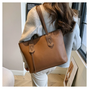 Detail of brown litchi pattern leather tote bag with fine stitching and slim shoulder straps