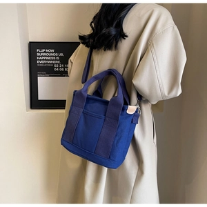 Detail of dark blue canvas tote bag with reinforced handles and sturdy metal hardware