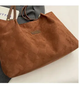Detail of brown quilted suede tote bag with elegant diamond stitching and slim shoulder straps