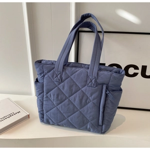 Detail view of the blue quilted nylon tote bag with side pocket and sleek zipper feature