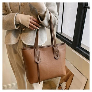 Deep brown lychee pattern leather tote bag shown with a grey wool coat on a model