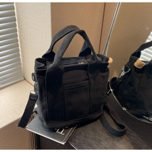 Detail of black canvas tote bag showing thick texture and adjustable crossbody strap
