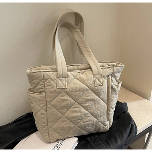 Close-up of beige quilted nylon tote bag with rhombus pattern and side pocket detail