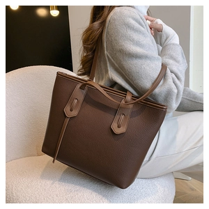 Detail of dark brown tote bag showing pebbled leather texture and wrapped handle