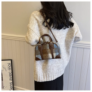 Model showing a brown plaid faux fur Boston bag with leather handles and a beige sweater