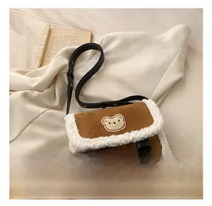 Détail du sac bandoulière en daim marron avec bordure en sherpa blanc et patch ours